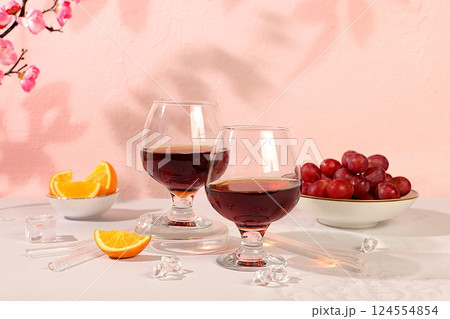 Modern still life with glass of gin or tequila, orange slices, ice and grapes on elegant background with sakura flowers, minimalist bar and summer party concept, advertising banner and menu for cafe Modern still life with glass of gin or tequila, orange slices, ice and grapes on elegant background with sakura flowers, minimalist bar and summer party concept, advertising banner and menu for cafe 124554854