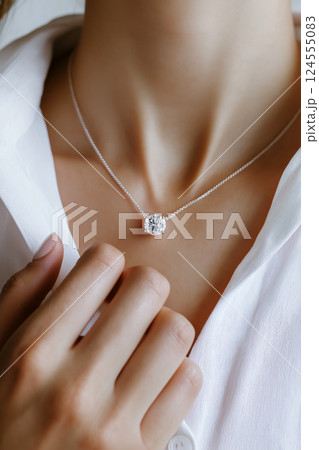 Elegant jewelry closeup featuring a diamond necklace on a delicate chain. Closeup of a diamond necklace on a neck emphasizes sophistication and beauty. Luxury jewelry, white gold and diamonds. Elegant jewelry closeup featuring a diamond necklace on a delicate chain. Closeup of a diamond necklace on a neck emphasizes sophistication and beauty. Luxury jewelry, white gold and diamonds. 124555083