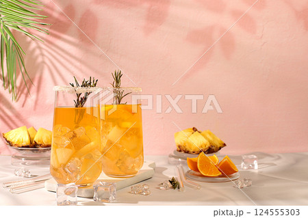 Detox diet and summer party concept. Cold homemade cocktail or lemonade with rosemary, orange, ice and pineapple on a sunny table, Refreshing summer diet drink recipe, restaurant menu, selective 124555303