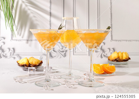 Summer party concept. Tequila, rum and vodka cocktail with pineapple, orange, ice and rosemary slices. Diet drink for body detox and weight loss, advertising for a bar or cafe, menu for a restaurant 124555305