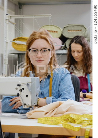 Three women seamstresses and fashion designers work in for sewing machines, clothing production. Three women seamstresses and fashion designers work in for sewing machines, clothing production. 124555490
