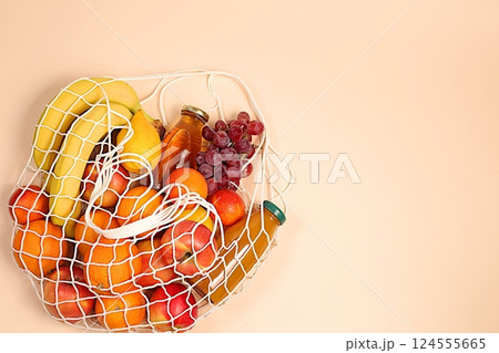 Lemons, oranges, tomatoes, apples, bananas, grapes and natural juice in a reusable bag, Fabric string bag with healthy vegan products for weight loss. food delivery concept, store advertising Lemons, oranges, tomatoes, apples, bananas, grapes and natural juice in a reusable bag, Fabric string bag with healthy vegan products for weight loss. food delivery concept, store advertising 124555665