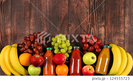 Healthy vegan products for a healthy lifestyle. Grapes, oranges, pineapple, apples, bananas, nuts and natural juice on a wooden background, detox diet and weight loss concept, store advertisement 124555723