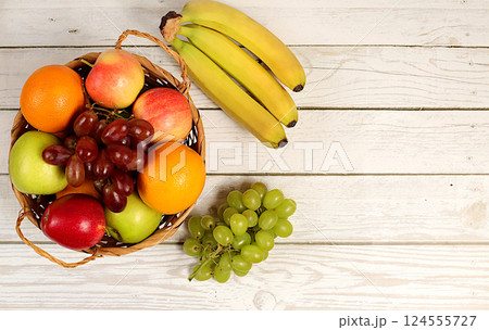 Healthy vegan products for a healthy lifestyle. Grapes, oranges, pineapple, apples, bananas, nuts and natural juice on a wooden background, detox diet and weight loss concept, store advertisement Healthy vegan products for a healthy lifestyle. Grapes, oranges, pineapple, apples, bananas, nuts and natural juice on a wooden background, detox diet and weight loss concept, store advertisement 124555727