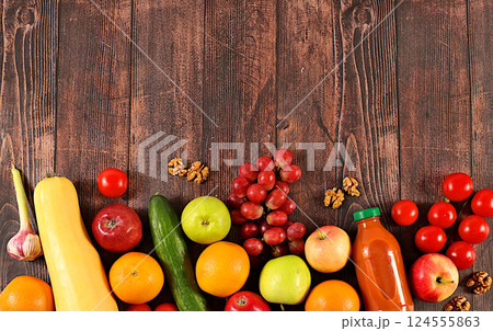 Grapes, oranges, tomatoes, apples, bananas, nuts and natural juice on a wooden background, detox diet and weight loss concept, healthy vegan products for a healthy lifestyle, advertising for a store 124555863