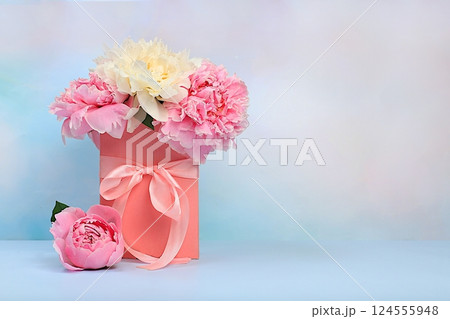 Delicate flowers of peonies and roses in a pink gift box. Abstract flower arrangement, concept of gifts for a holiday, birthday, wedding and mother's day. Spring still life and banner for the screen 124555948