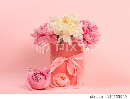 Delicate flowers of peonies and roses in a pink gift box. Abstract flower arrangement, concept of gifts for a holiday, birthday, wedding and mother's day. Spring still life and banner for the screen 124555949