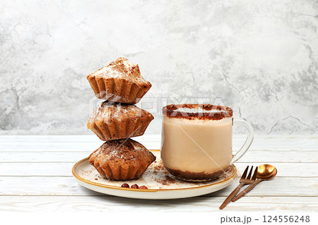 Chocolate muffins with nutmeg and cinnamon eggnog on a concrete background, cozy breakfast concept, advertising for a cafe or bakery. Warming egg drink in cold season with delicious dessert, selective Chocolate muffins with nutmeg and cinnamon eggnog on a concrete background, cozy breakfast concept, advertising for a cafe or bakery. Warming egg drink in cold season with delicious dessert, selective 124556248