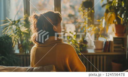 Woman gazing out a sunny window, reflective. 124556478