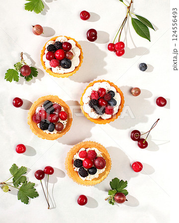 Delicious tartlets with fresh berries raspberries, cherries, gooseberries and blueberries. Cupcakes with soft curd cream, summer dessert. Concept of a modern bakery, advertising for a cafe, Delicious tartlets with fresh berries raspberries, cherries, gooseberries and blueberries. Cupcakes with soft curd cream, summer dessert. Concept of a modern bakery, advertising for a cafe, 124556493