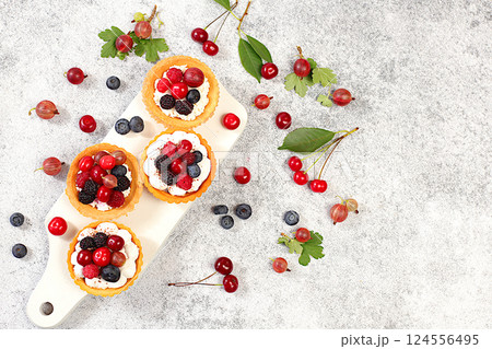 Delicious tartlets with fresh berries raspberries, cherries, gooseberries and blueberries. Cupcakes with soft curd cream, summer dessert. Concept of a modern bakery, advertising for a cafe, Delicious tartlets with fresh berries raspberries, cherries, gooseberries and blueberries. Cupcakes with soft curd cream, summer dessert. Concept of a modern bakery, advertising for a cafe, 124556495
