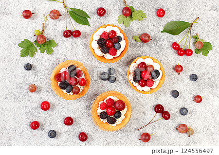 Cupcakes with soft curd cream, Delicious tartlets with fresh berries raspberries, cherries, gooseberries and blueberries. Summer dessert. Concept of a modern bakery, advertising for a cafe, 124556497