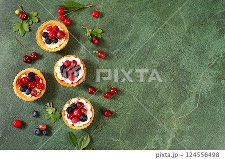 Cupcakes with soft curd cream, Delicious tartlets with fresh berries raspberries, cherries, gooseberries and blueberries. Summer dessert. Concept of a modern bakery, advertising for a cafe, Cupcakes with soft curd cream, Delicious tartlets with fresh berries raspberries, cherries, gooseberries and blueberries. Summer dessert. Concept of a modern bakery, advertising for a cafe, 124556498