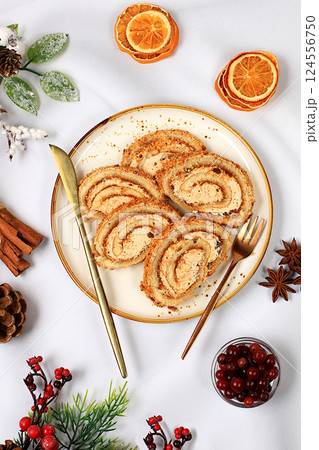 Homemade winter dessert, stollen or strudel with sweet cream filling, nuts, cinnamon and poppy seeds. Concept for holiday bakery, seasonal treats and cafe advertising, selective focus 124556750