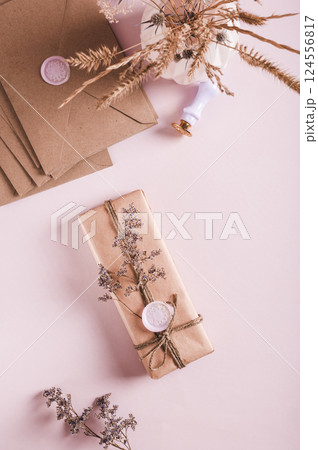 Gift in craft paper with wax seal and dried flowers on pink top and vertical view Gift in craft paper with wax seal and dried flowers on pink top and vertical view 124556817