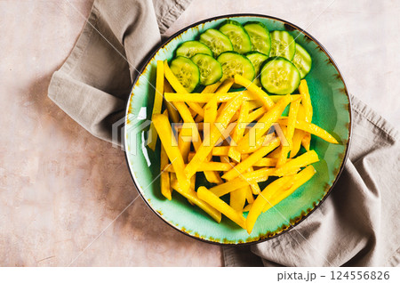 Close up of appetizing French fries and cucumber slices on a plate on the table top view Close up of appetizing French fries and cucumber slices on a plate on the table top view 124556826