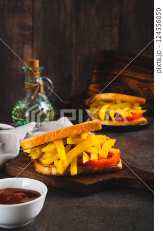 Fried toasts with french fries and tomato on a board on the table vertical view Fried toasts with french fries and tomato on a board on the table vertical view 124556850