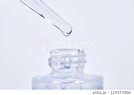 The blue serum drips from the dropper into the bottle. The blue serum drips from the dropper into the bottle. 124557066