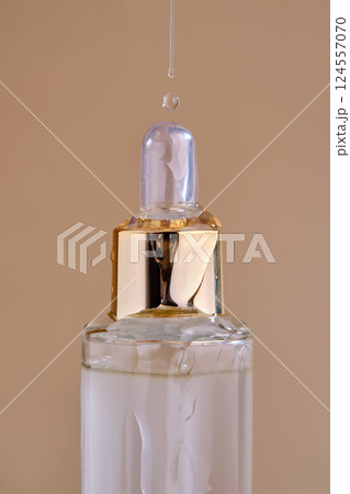 A bottle of cosmetic product with a pouring texture on top. A bottle of cosmetic product with a pouring texture on top. 124557070