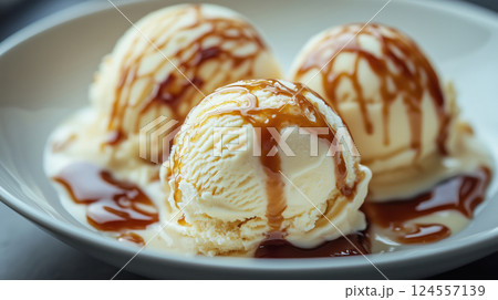 Vanilla ice cream scoops with caramel sauce on white plate 124557139
