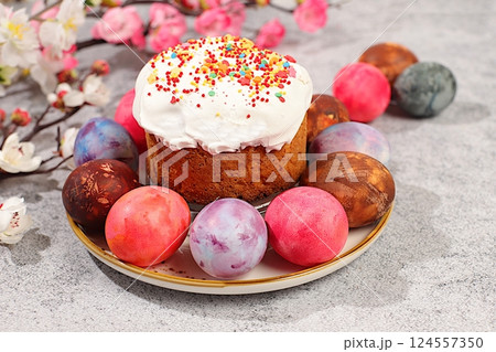 Easter celebration concept, traditional kulich and marble Easter eggs painted with onion peel, hibiscus tea and pink matcha with sakura branches, ideas for homemade Easter dishes. 124557350