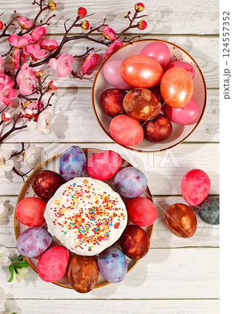 Traditional kulich and marbled Easter eggs painted with onion peel, hibiscus tea and pink matcha with sakura branches, Easter celebration concept, Easter dish ideas for home cooking. 124557352