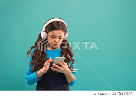schoolgirl use digital device. casual fashion for kids. kid long hair listen music in headset. small child make play list on smartphone. small girl use mp3 player. study in modern life. copy space 124557474