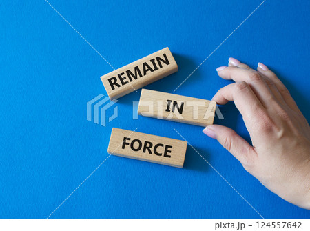 Remain in Force symbol. Concept words Remain in Force on wooden blocks. Businessman hand. Beautiful blue background. Business and Remain in Force concept. Copy space Remain in Force symbol. Concept words Remain in Force on wooden blocks. Businessman hand. Beautiful blue background. Business and Remain in Force concept. Copy space 124557642