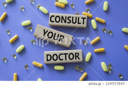 Consult Your Doctor symbol. Concept word Consult Your Doctor on wooden blocks. Beautiful purple background with pills. Medicine and Consult Your Doctor concept. Copy space Consult Your Doctor symbol. Concept word Consult Your Doctor on wooden blocks. Beautiful purple background with pills. Medicine and Consult Your Doctor concept. Copy space 124557647