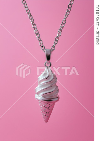 Elegant silver ice cream cone necklace on a soft pink background. White gold ice cream cone jewelry pendant. Sweets and fast fashion concept. Rip diet, creative jewelry. Summer vibes, holidays. 124558131