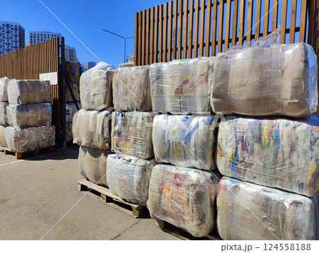 Large bundles of compressed paper waste, wrapped in plastic, waiting to be processed at an urban recycling plant. Large bundles of compressed paper waste, wrapped in plastic, waiting to be processed at an urban recycling plant. 124558188