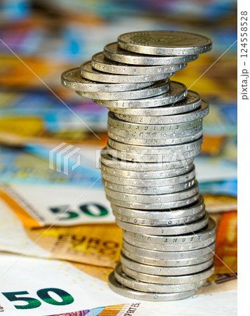 Wobbly pyramid of two euro coins on a background of euro banknotes, concept of a stagnant economy 124558528