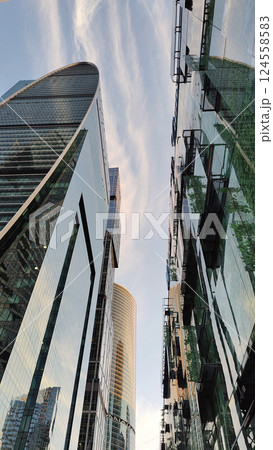 A cityscape featuring modern high-rise buildings with reflective glass facades, capturing the warm hues of sunset. 124558583