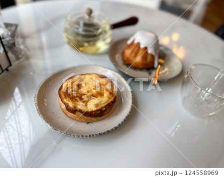 Pastry tart and glazed cake served with herbal tea on a cafe table. Cozy break and slow lifestyle with light sweet food Pastry tart and glazed cake served with herbal tea on a cafe table. Cozy break and slow lifestyle with light sweet food 124558969