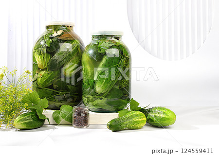 Pickled cucumbers in a jar with garlic and dill on the kitchen table, village harvest, homemade pickling recipe, cucumbers and ingredients for pickling, home canning concept, healthy and natural food. 124559411
