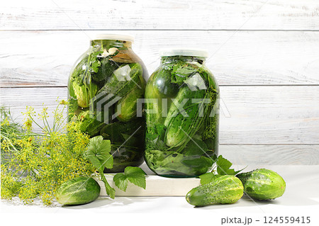 Pickled cucumbers in a jar with garlic and dill on the kitchen table, village harvest, homemade pickling recipe, cucumbers and ingredients for pickling, home canning concept, healthy and natural food. 124559415