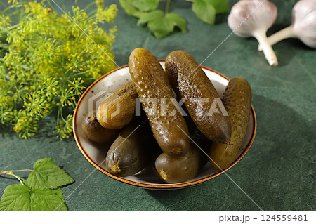 Fresh pickled cucumbers in a bowl with garlic and dill on a concrete table, village harvest, homemade pickling recipe, cucumbers and ingredients for pickling, home canning concept, 124559481