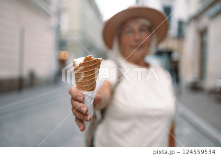 A senior woman enjoying a delicious ice cream cone on a sunny day in the city 124559534