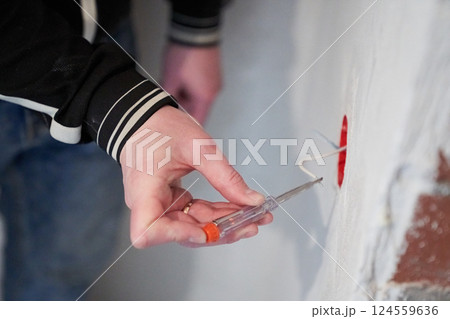 A man checks the current in a junction box with electrical wires using an indicator screwdriver. The concept of repair and troubleshooting of an outlet.Replace the electrical outlet.High quality photo 124559636