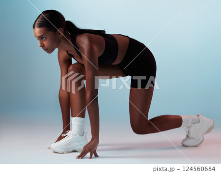 Start position, runner and fitness woman in studio ready for marathon, exercise or cardio workout. Motivation, run and athlete or model from India doing sports training isolated by a blue background. Start position, runner and fitness woman in studio ready for marathon, exercise or cardio workout. Motivation, run and athlete or model from India doing sports training isolated by a blue background. 124560684