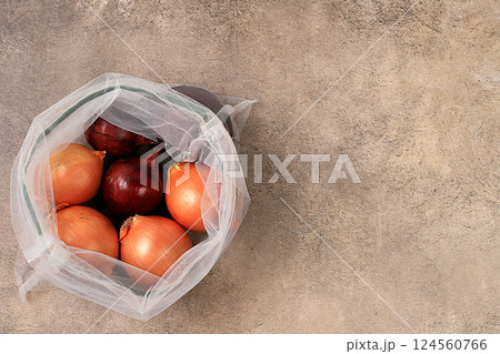 Various varieties of onions in fabric packaging. Healthy natural products in an eco bag to boost immunity, healthy lifestyle concept, zero waste. Banner for the store. No plastic. Selective focus 124560766