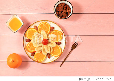 Healthy breakfast with ingredients, fun food for kids, food decoration ideas, healthy and natural food concept. Flower of bananas, oranges and nuts on a plate, selective focus. 124560897