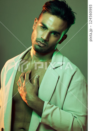 Beauty, green lights and portrait of sexy man from India touching bare chest in creative studio shoot. Fashion, neon light and professional male model, single Indian man with seductive and sexy style 124560993