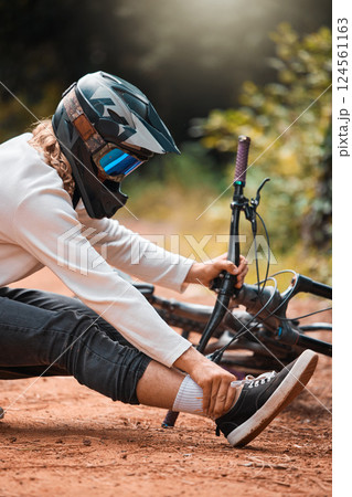Ankle pain, cycling and man on the ground in a park with injured foot, pain and accident while riding bike for fitness. Foot pain, bicycle and dirt road accident, cyclist and foot injury in a forest 124561163