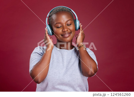 Black woman, headphones and smile for music listening, streaming or relax against a studio background. African American female with smile enjoying audio track, hifi or relaxing with wireless headset Black woman, headphones and smile for music listening, streaming or relax against a studio background. African American female with smile enjoying audio track, hifi or relaxing with wireless headset 124561260