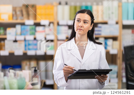 Woman pharmacist makes restock, uses electronic carrier tablet of information Woman pharmacist makes restock, uses electronic carrier tablet of information 124561291