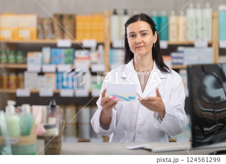 Middle-aged female pharmacist offering preparation in box Middle-aged female pharmacist offering preparation in box 124561299