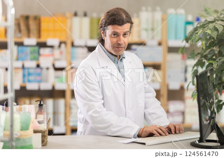 Pharmacist in uniform looking for medicine in pharmacy using computer Pharmacist in uniform looking for medicine in pharmacy using computer 124561470