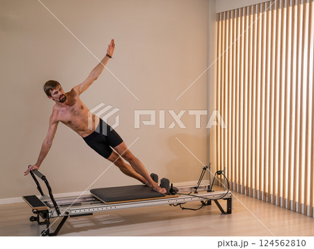 A man doing Pilates on a reformer.  124562810