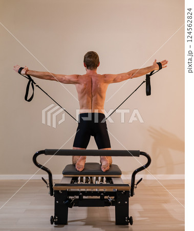 A man doing Pilates on a reformer. A man doing Pilates on a reformer. 124562824